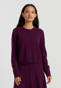 Cardigan viola realizzato in morbido tessuto, con scollo rotondo, chiusura a cinque bottoni, maniche lunghe e polsini e orlo a coste.