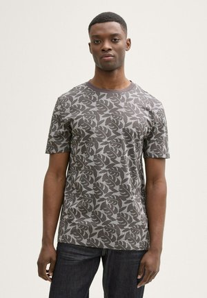 Grijze T-shirt met korte mouwen en een bladdessin in donkergrijs. Ronde halslijn en zachte, textuurrijke katoenstof. Gededragen met donkere jeans.