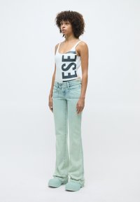 Body blanc avec de grandes lettres noires, assorti à un jean taille haute bleu clair et des chaussures chunky vert menthe.