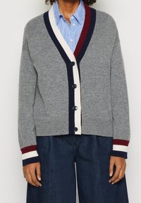 Cardigan grigio con scollo a V, chiusura con bottoni e strisce a contrasto blu navy e bordeaux su collo e polsini. Morbida consistenza.