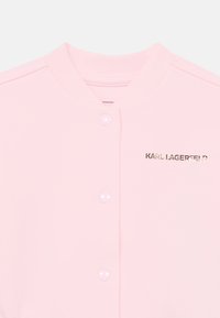 Ροζ σακάκι με κουμπιά από μαλακό ύφασμα, με στρογγυλή γιακά, δύο γυαλιστερά κουμπιά και το "KARL LAGERFELD" τυπωμένο σε χρυσό.