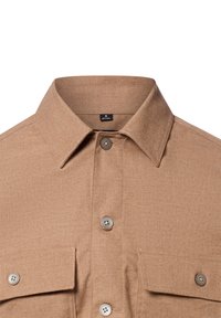 Camicia a maniche corte di colore marrone chiaro con colletto classico, due tasche sul petto e apertura con bottoni. Realizzata in un tessuto strutturato con variazioni sottili.