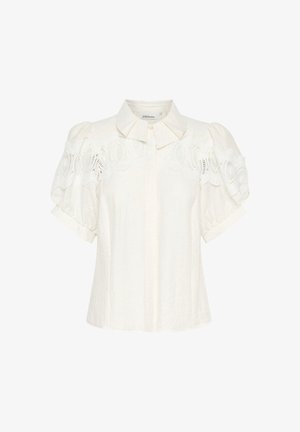 White linen blouse with a collared neckline, short puff sleeves, and intricate lace detail along the shoulders. Textured, lightweight fabric.