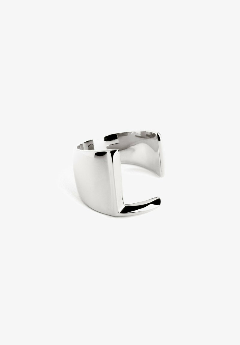 Anello in metallo argentato con superficie liscia e lucida, caratterizzato da un design geometrico aperto e dettagli a taglio angolare.