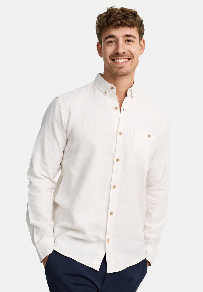 Camisa de lino blanca de manga larga con cuello abotonado, un bolsillo en el pecho y botones marrones en la tapeta. Textura suave, corte relajado.