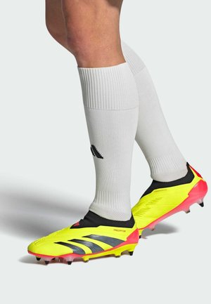 Botas de fútbol de color amarillo brillante con rayas negras y acentos rosas, acompañadas de calcetas blancas hasta la rodilla con un logotipo negro.