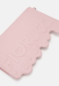 Rozā ādas maku ar viļņotu malu un izceltu pietuvinājuma dizainu. Ar rāvējslēdzēju aizdarīšana, gluda tekstūra.