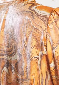 Marbled fabric in orange and brown with metallic silver accents, featuring wavy patterns and a soft, textured surface.