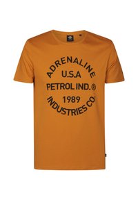 Camiseta de algodón naranja con un logo redondo que dice "ADRENALINE U.S.A. PETROL IND. 1989 INDUSTRIES CO." en texto negro en negrita. Manga corta y cuello redondo.