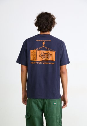 Tricou din bumbac de culoare albastru închis, cu un grafic portocalie care ilustrează un macarale ridicând un container de marfă și textul "Dickies HEAVY DUTY WORKWEAR."