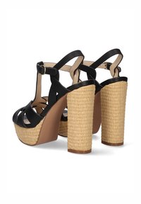 Sandalias de tacón alto negras con tiras, con plataforma y tacón de paja trenzada, que cuentan con un cierre de hebilla y un diseño de espalda descubierta.