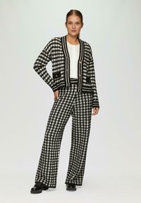 Zwart-wit geblokt twee-delig setje met een korte cardigan met zakken en een paar wijde broekspijpen. Getextureerde gebreide stof.