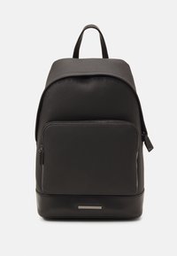 Zaino in pelle nera con superficie texture, parte superiore arrotondata, tasca frontale con zip e un dettaglio metallico alla base. Spallacci regolabili non visibili.