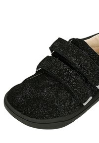 Scarpe velcro nere con una superficie texture e glitterata, dotate di punta tondeggiante e una robusta suola in gomma nera.