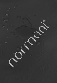 Schwarzer, wasserdichter Stoff mit einer strukturierten Oberfläche, der das silberne "normani"-Logo und mehrere Wassertröpfchen auf dem Material zeigt.
