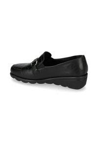 Mocassino in pelle nera con tomaia lavorata, dettaglio in metallo argentato, pannello laterale elasticizzato e suola spessa e imbottita.