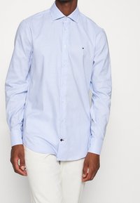 Blau kariertes Langarmhemd mit Button-Down-Kragen. Verfügt über weiße Knöpfe und ein kleines Logo auf der Brust. Hergestellt aus leichtem Stoff.