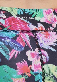 Maillot de bain à motifs floraux avec des couleurs vives sur un fond sombre, présentant une texture lisse et des accents de couture noire.
