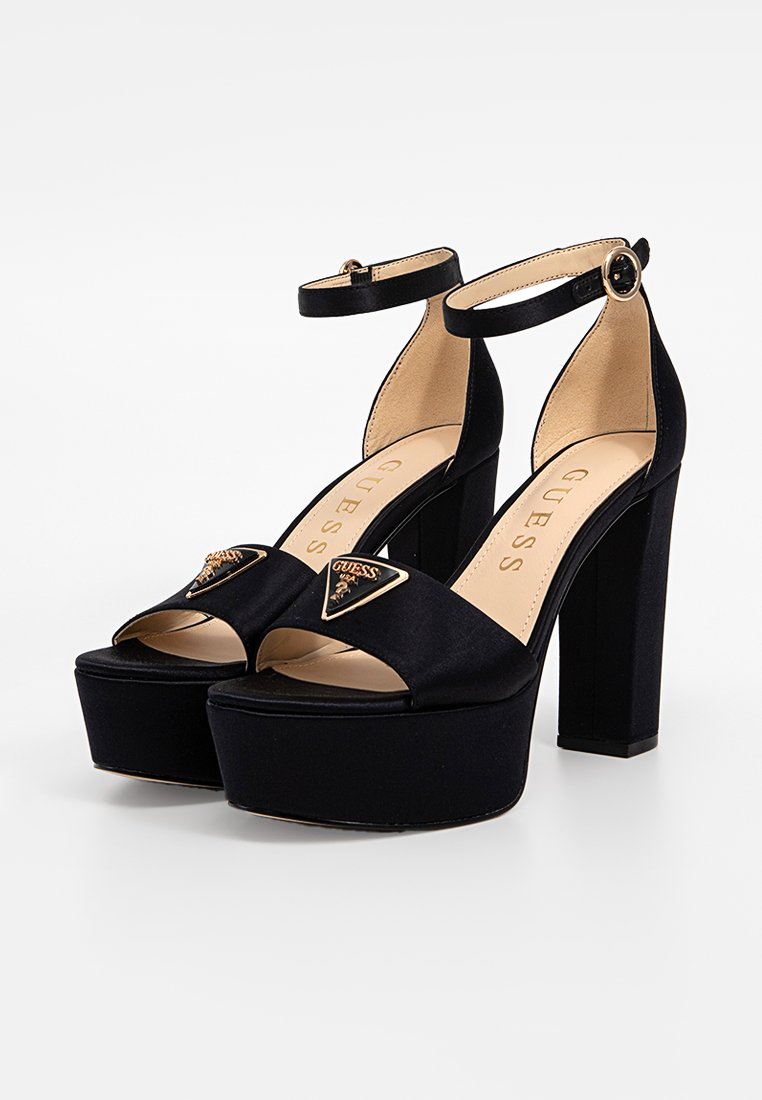 Sandales à plateforme noires avec une finition satinée, bout ouvert, bride de cheville et un accent de logo triangulaire à l'avant. Design avec un talon carré.