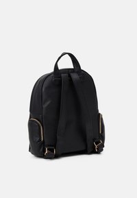 Black leather backpack with a rounded shape, two shoulder straps, a top handle, and gold zipper accents on side pockets. Textured surface.