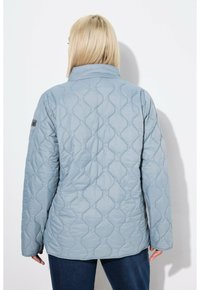 Chaqueta acolchada de color azul claro, con cuello alto, que presenta un patrón de diamantes, mangas largas y una textura suave y lisa.
