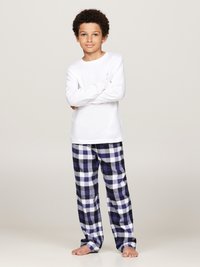 Chemise blanche à manches longues associée à un pantalon de pyjama à carreaux bleu marine et blanc. Le tissu semble doux, avec une coupe décontractée et sans accents visibles.