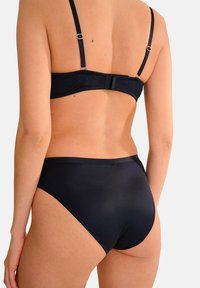 Zwarte bikini met verstelbare bandjes, een haaksluiting op de rug en hoge taille broekjes. Glad, glanzend stofoppervlak.