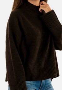 Maglione marrone scuro in lana con collo alto a costine, spalle basse e polsini a costine, caratterizzato da una vestibilità rilassata e una texture morbida.