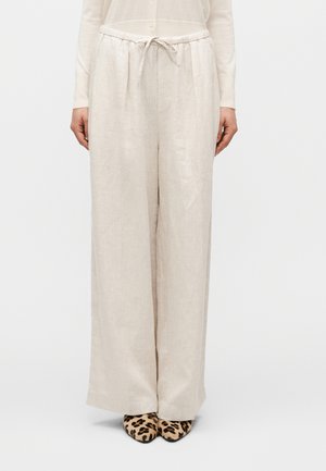 Lyse beige vidbenede linnedbukser med elastisk taljebånd og bindedetalje, lavet i et tekstureret stof. Båret med leopardmønstrede sko.