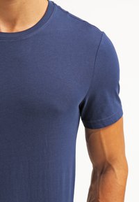 Navy blue cotton t-shirt with a crew neck and short sleeves. Smooth texture and fitted design, showcasing the shoulder and arm details.