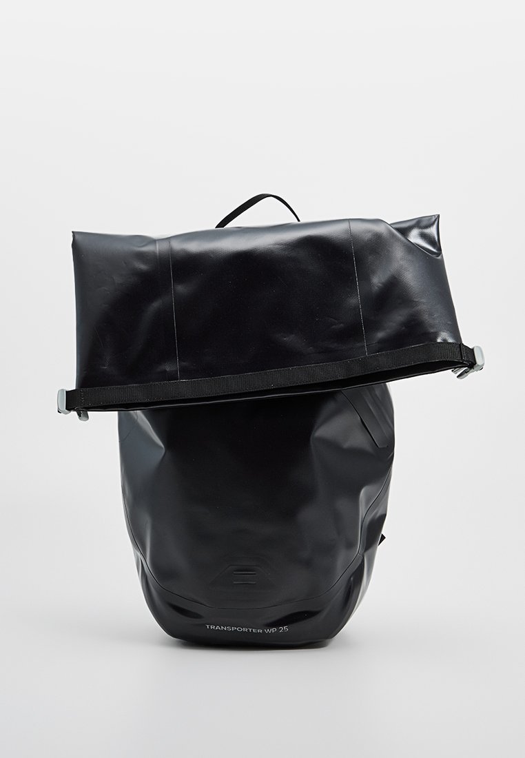 Sac à dos étanche noir avec un design à rabat, en matériau durable, avec une sangle réglable et un logo sur le devant. Texture lisse avec quincaillerie cachée.