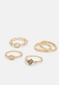 Set aus vier goldenen Ringen mit unterschiedlichen Designs: einer mit einer glatten Ovalform, einer mit einem quadratischen Stein, strukturierten Bändern und einer mit einem Kettenmuster.