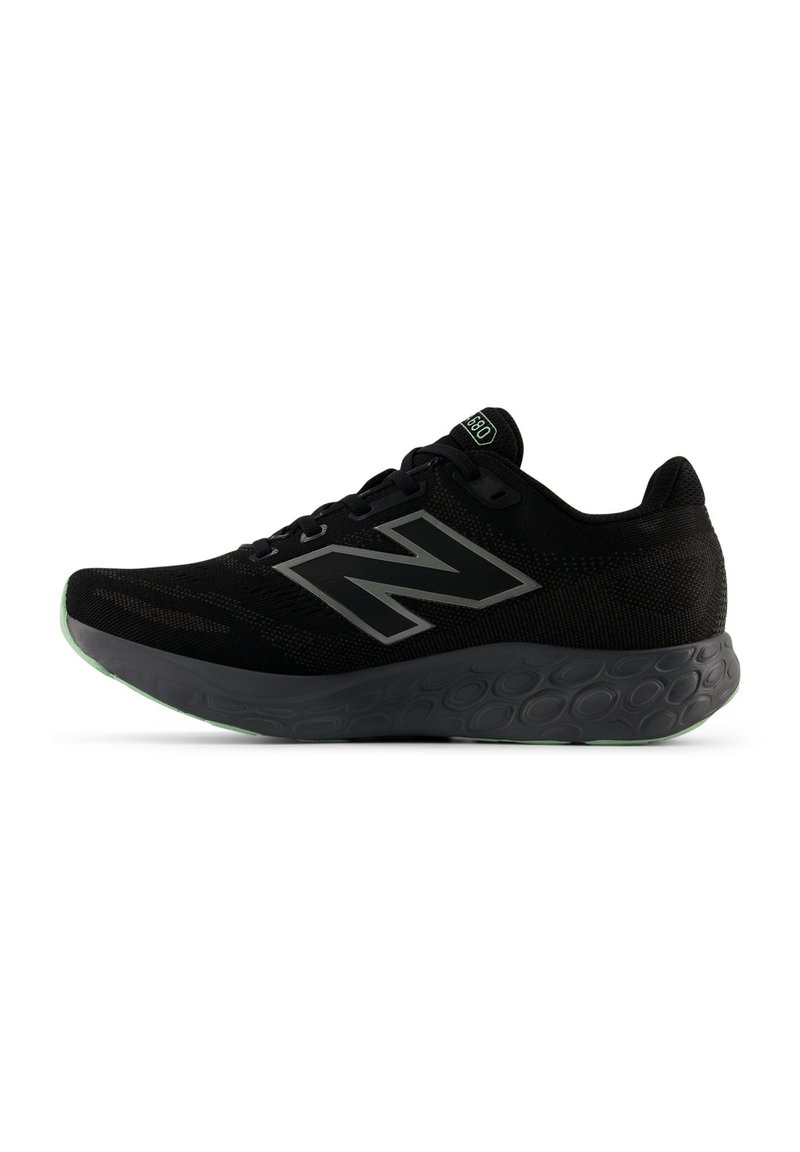 Zwarte New Balance hardloopschoen met mesh bovenwerk, groot "N"-logo, gemusterde tussenzool en groene accenten op de zool en het label van de tong.