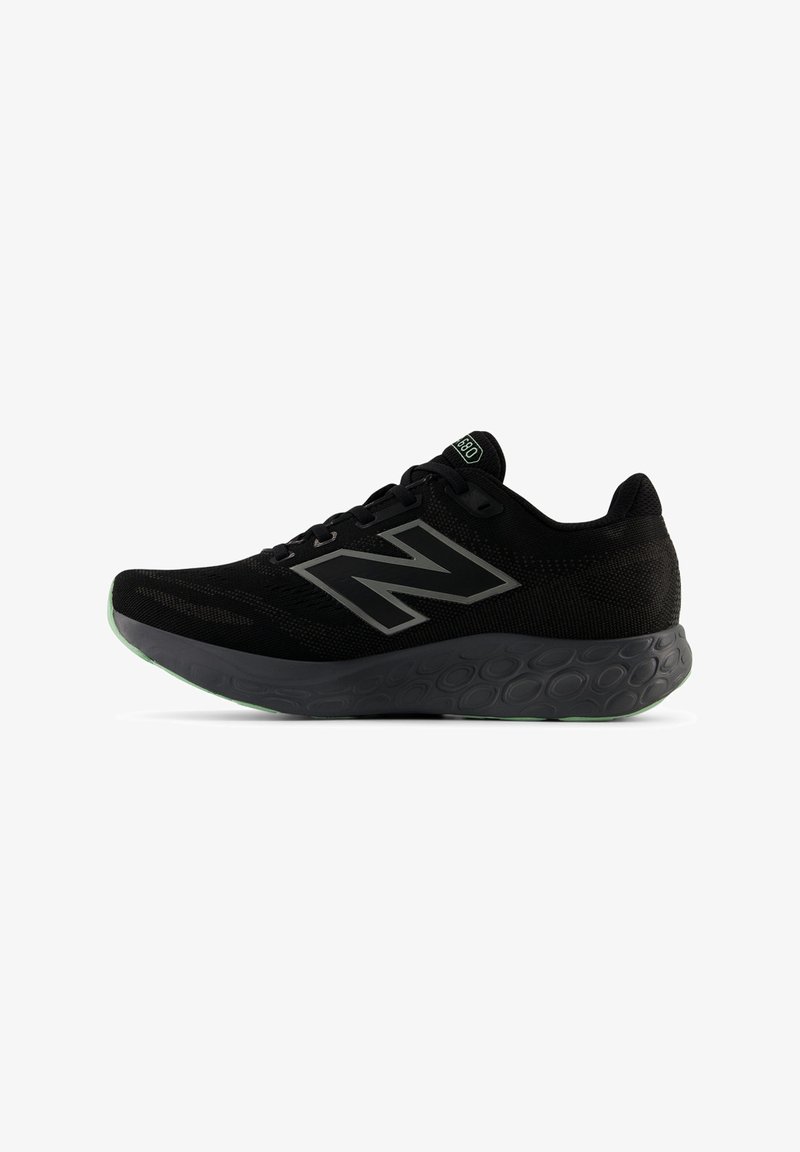 Zwarte New Balance hardloopschoen met mesh bovenwerk, groot "N"-logo, gemusterde tussenzool en groene accenten op de zool en het label van de tong.