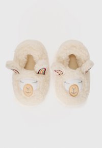 Chaussons de couleur crème en matériau pelucheux, présentant un visage de lama avec des détails brodés et des accents colorés sur les oreilles.