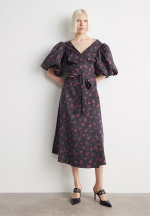 Dark floral wrap dress with puff sleeves, featuring pink blossoms, a tie waist, and a flowing skirt. Worn with black pointed heels.