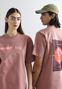 Pink cotton t-shirts with short sleeves. Front features "HELMUT LANG" logo; back shows graphic design with a circle and text.