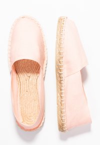 Espadrilles made of pink canvas with a woven jute sole, featuring a soft texture and rounded toe design. Stitching visible along the edges.