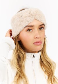 Faux fur haarband in beige met een gedraaide voorkant. Zachte textuur, brede vorm die comfortabel om het hoofd past en de warmte verhoogt.