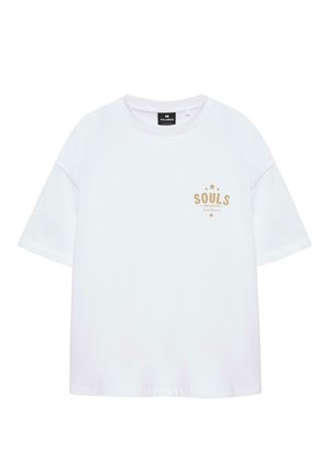 T-shirt blanc oversize à manches courtes avec le texte beige "SOULS Unbroken Street Raised" et des motifs étoilés sur le côté gauche de la poitrine, col rond.