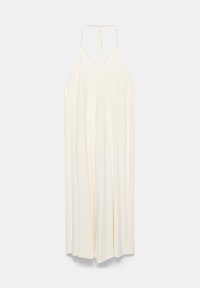 Longue robe sans manches couleur crème avec fines bretelles et coupe ample et fluide sur un fond clair.