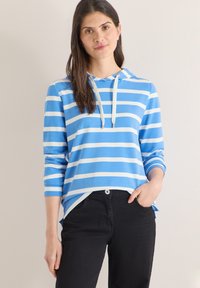 Sweat à capuche rayé bleu et blanc avec une poche avant, des manches longues et des cordons ajustables, associé à un pantalon noir. Texture de tissu lisse.