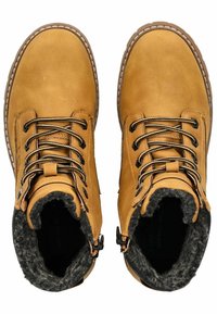Bottines en cuir marron avec doublure noire en fausse fourrure, bouts ronds, lacets noirs et fermetures éclair. Couture détaillée autour de la semelle.
