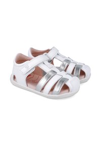 Sandalias blancas con detalles plateados, diseñadas con recortes y una correa de velcro. Fabricadas con material suave, presentan una plantilla acolchada.