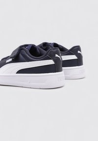 Sneaker blu navy con accenti bianchi, caratterizzati da una tomaia sintetica liscia, punta rotonda e chiusura con cinturino regolabile. Logo sul tallone e sul lato.