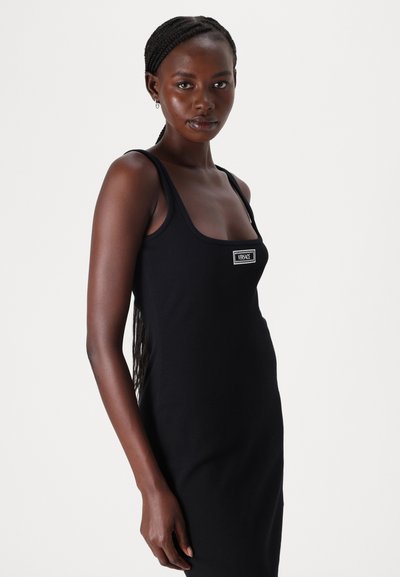 Rochie neagră fără mâneci, confecționată dintr-un material elastic, având un decolteu pătrat și un mic etichetă logo pe față, cu un design ajustat.