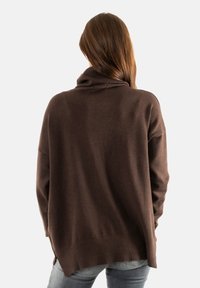 Maglione marrone sovradimensionato con collo alto, polsini e orlo a coste. Tessuto morbido, scivola liberamente sul corpo con un retro più lungo.