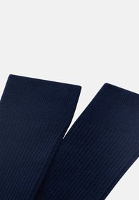 Marina-ribbad strumpor med en slät, texturerad yta. Har en bred, åtsittande mudd högst upp för komfort och stöd.