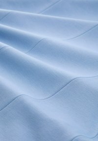 Textile with a smooth texture in light blue, featuring subtle wavy patterns. The fabric appears soft and flexible, suitable for various applications.