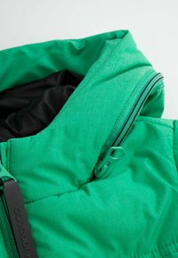Zielona kurtka puchowa z detalami, z teksturowaną powierzchnią, czarną podszewką i kontrastowym zamkiem z zielonym uchwytem.